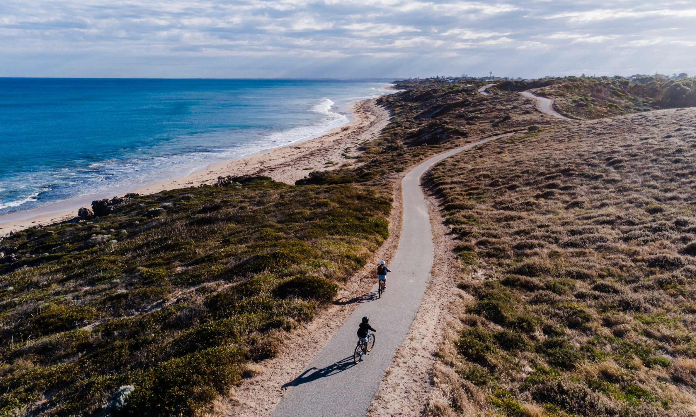 Cycling along Perth's coastal path with the city skyline in the background
